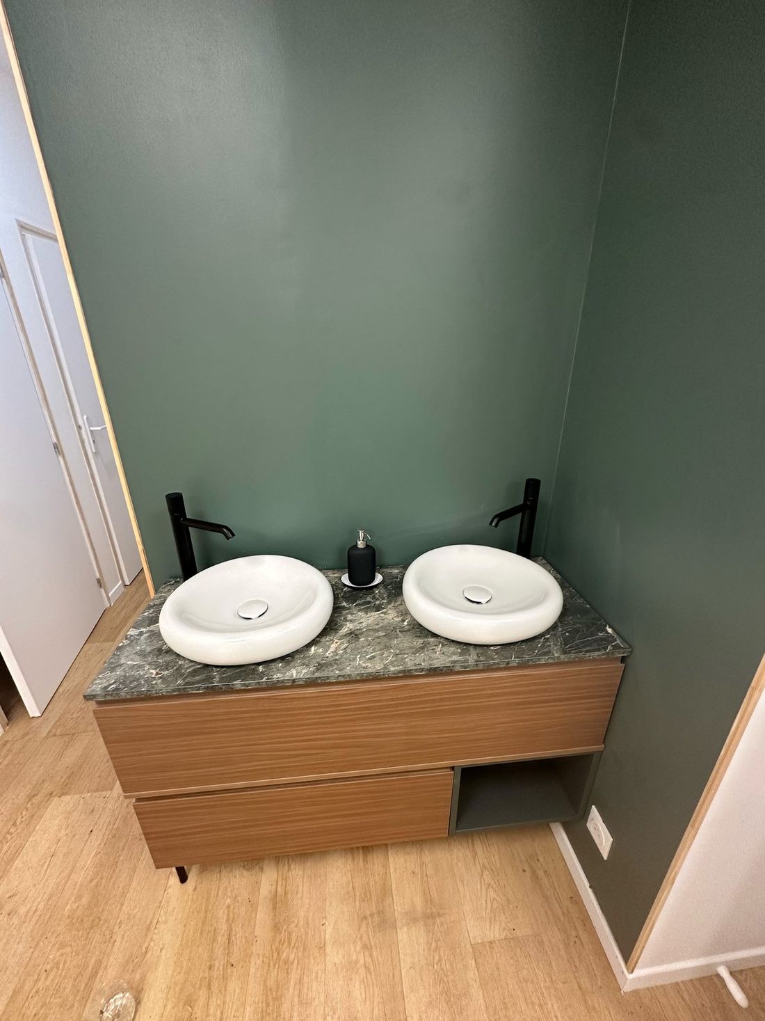 Double vasque sur meuble en bois devant un mur vert